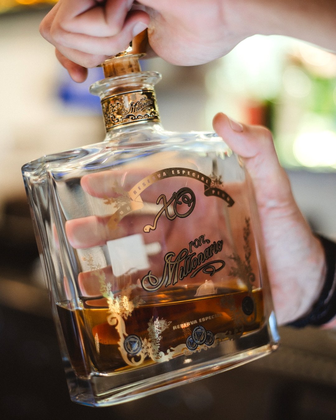 Hands opening a bottle of Ron Millonario rum