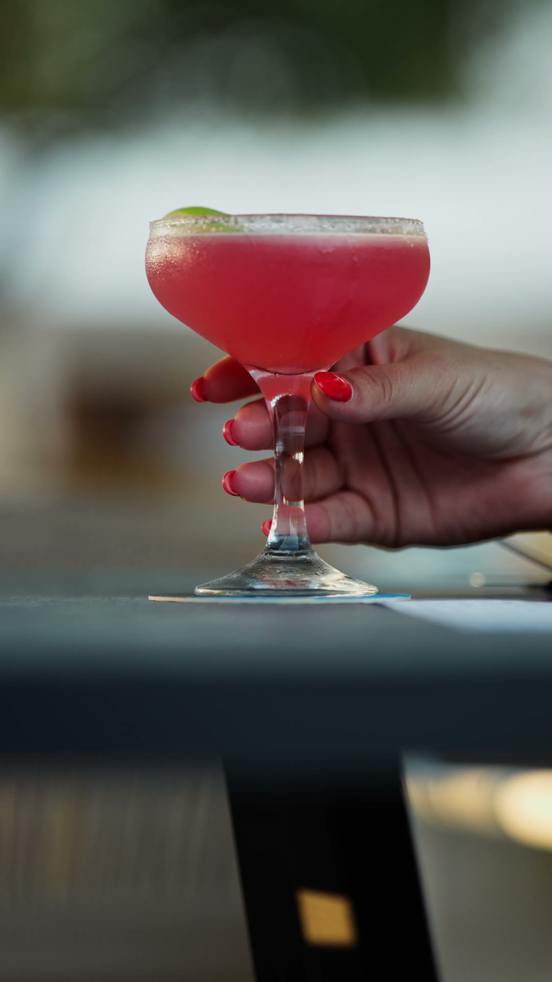 A rose-pink cocktail raised on the Madison terrace at dusk