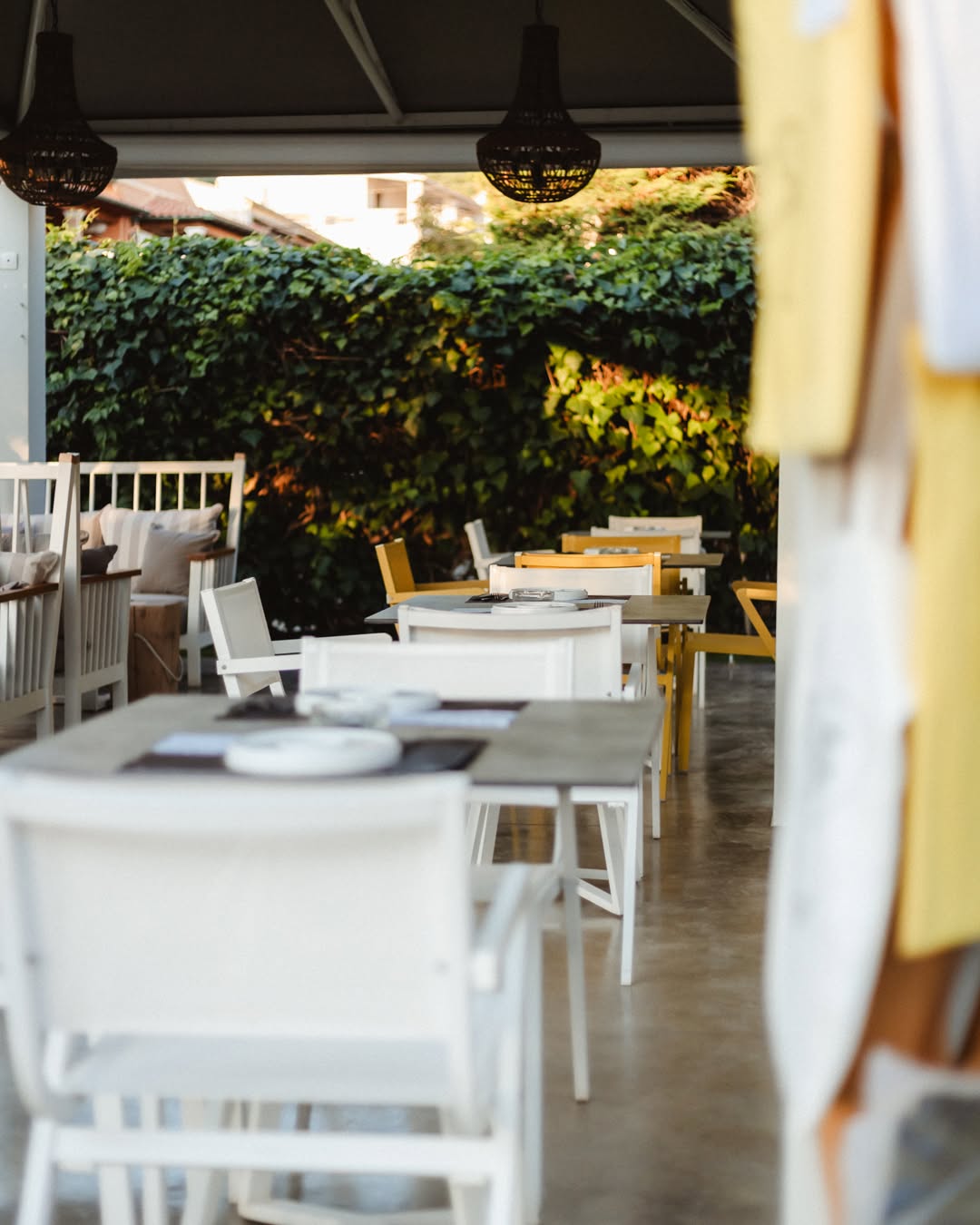 The terrace laid for evening service, golden light on white tables against the ivy wall
